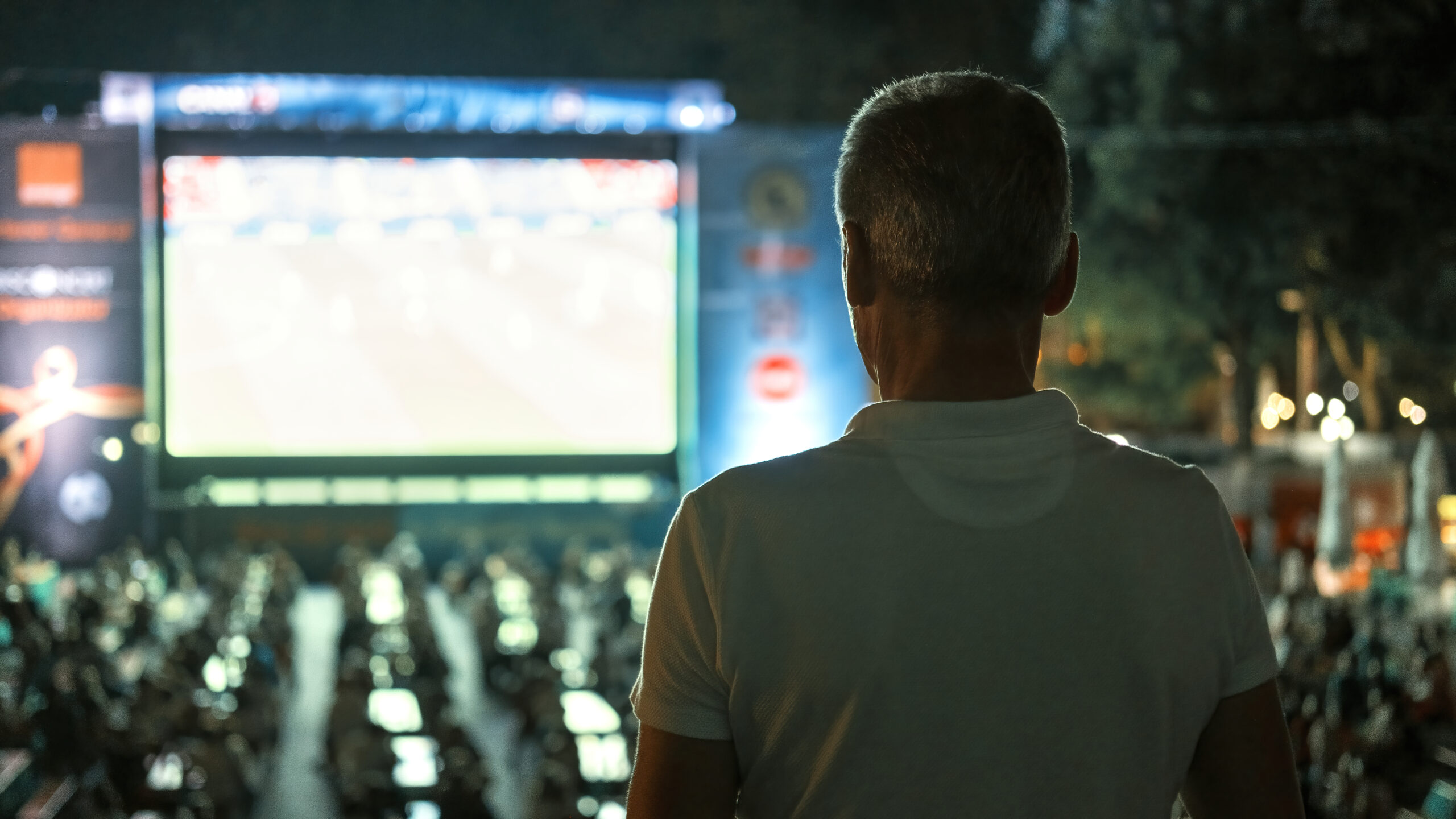 man watching football in a public place at night